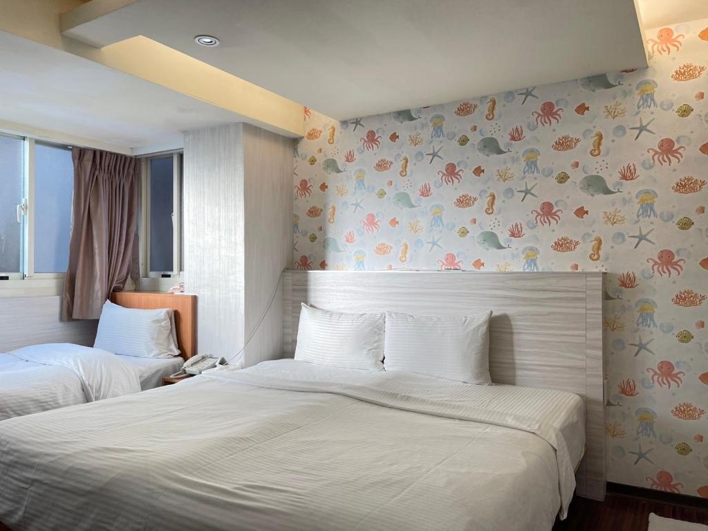 2 Betten in einem Schlafzimmer mit Blumen an der Wand in der Unterkunft Jung Shin Hotel in Zhongli