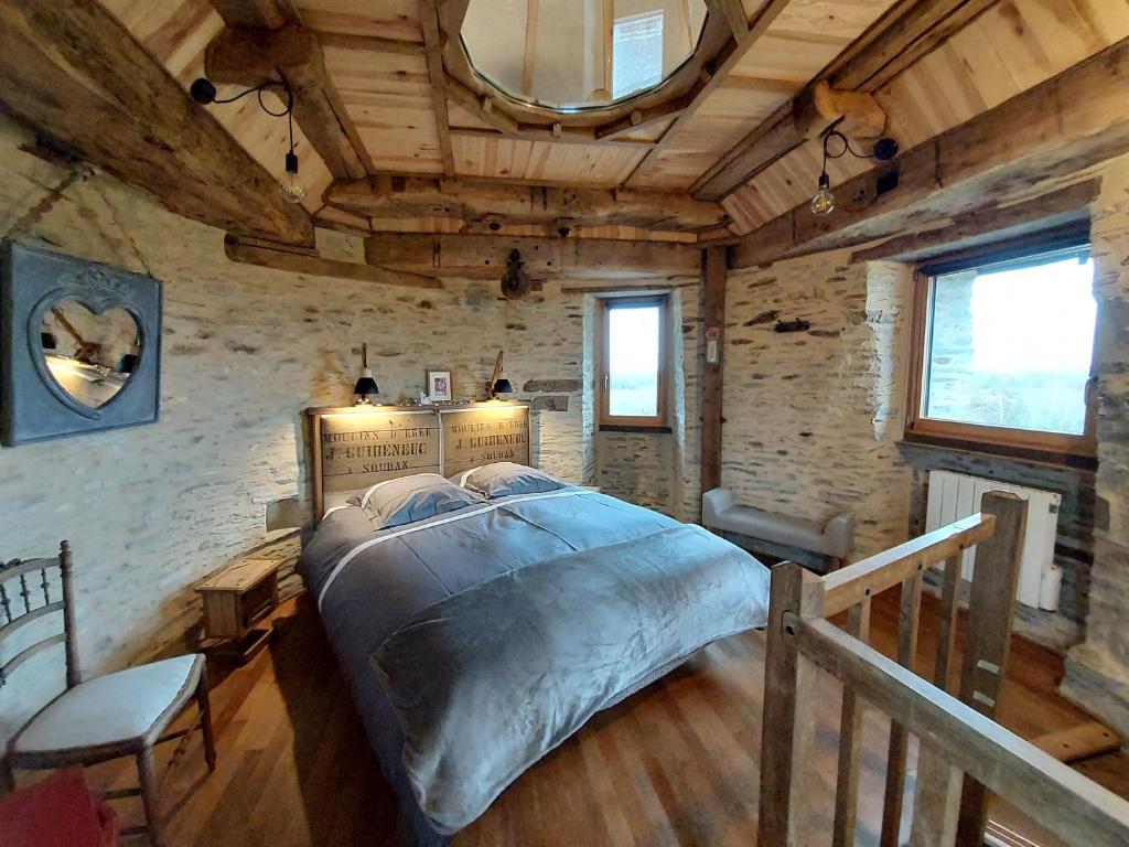 Un dormitorio con una cama grande en una habitación con techos de madera. en Le Moulin d' Erée, gîte Insolite de charme, en Soudan