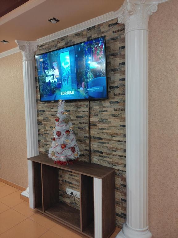 a christmas tree and a television on a brick wall at Comfortable Apartment in Kremenchuk
