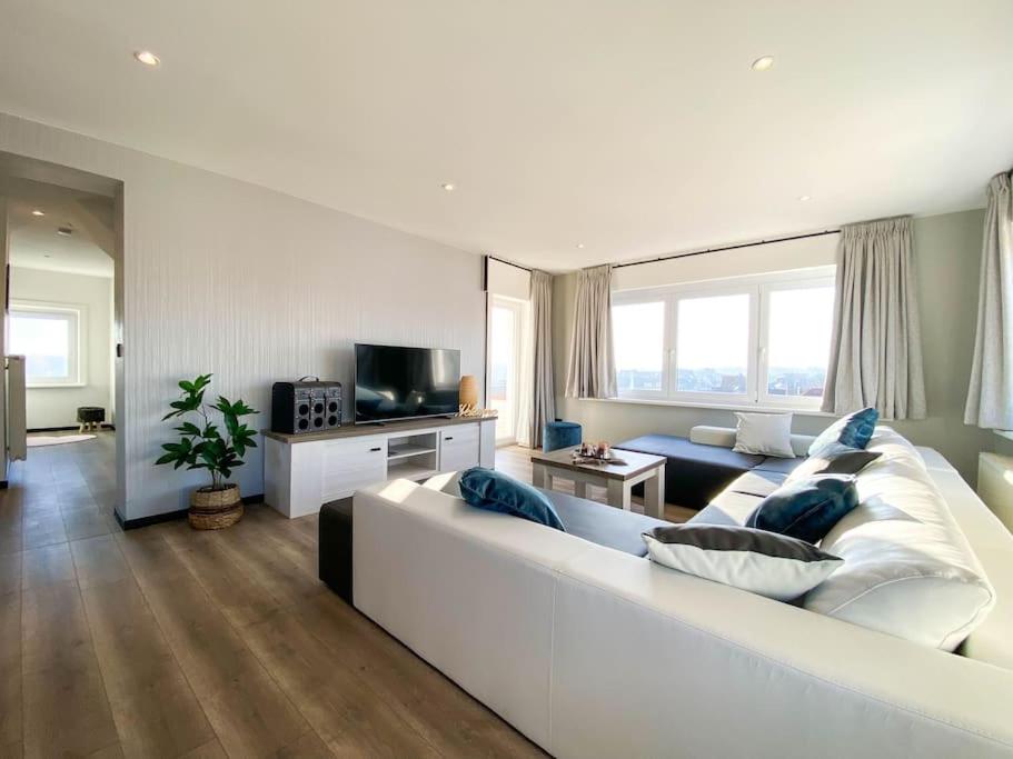 un ampio soggiorno bianco con un grande divano bianco di Loft Monaco - Ruime vakantieloft a De Panne