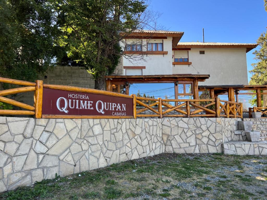 um sinal numa parede de pedra em frente a uma casa em Hostería y Cabañas Quime Quipan by Nordic em San Carlos de Bariloche