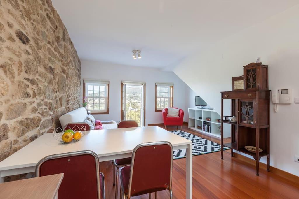 a living room with a stone wall and a table and chairs at Apartamentos Lumar in Valença