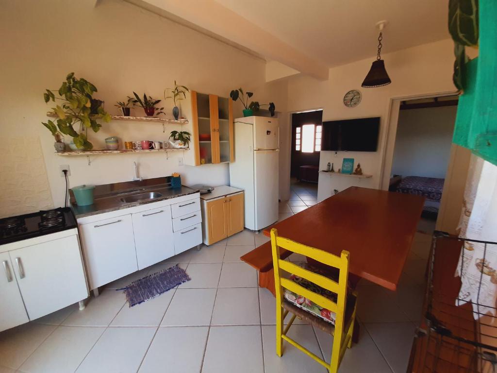 a kitchen with a table and a yellow chair in it at Pousada Encantos do Paraíso in Praia do Rosa