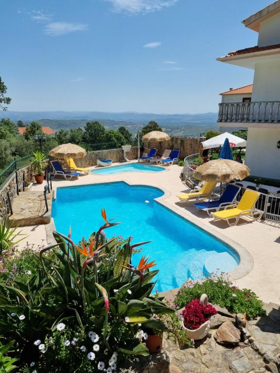 uma piscina com cadeiras e guarda-sóis ao lado de um edifício em Quinta do Ribeiro na Covilhã