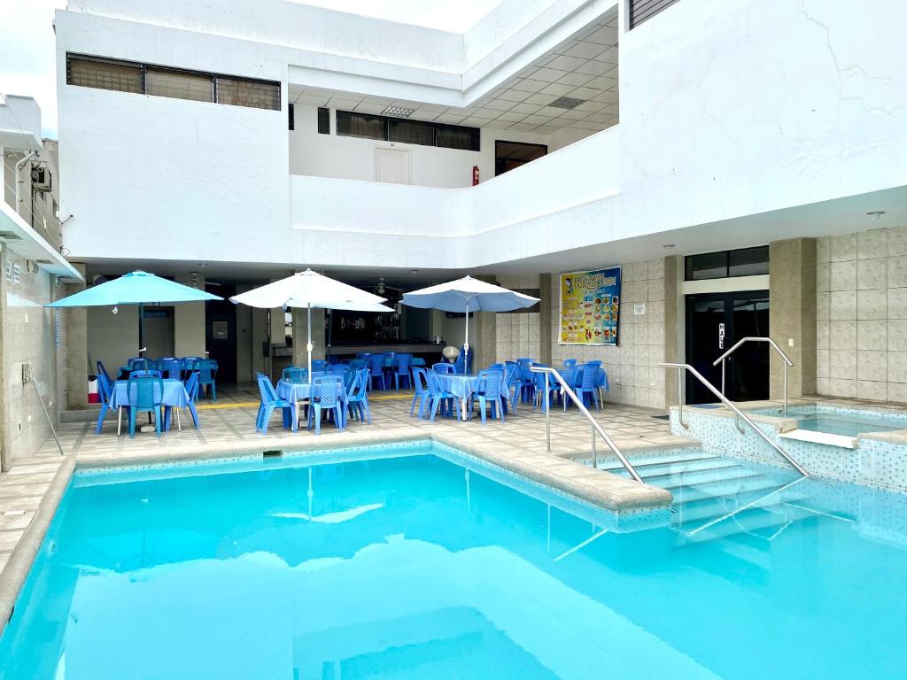 サリナスにあるHotel Dorado Innの青いテーブルと椅子、パラソル付きのプール