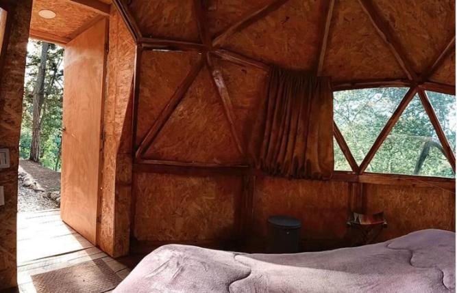 - une chambre avec une grande fenêtre dans une cabane en bois dans l'établissement Quinta de Fagua, à Sutatausa