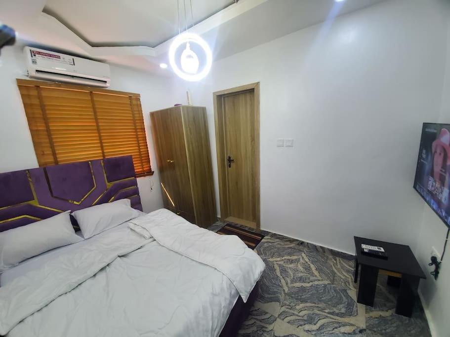 a bedroom with a bed and a night stand with at Dinero Ruby - Studio Apartment in Lagos