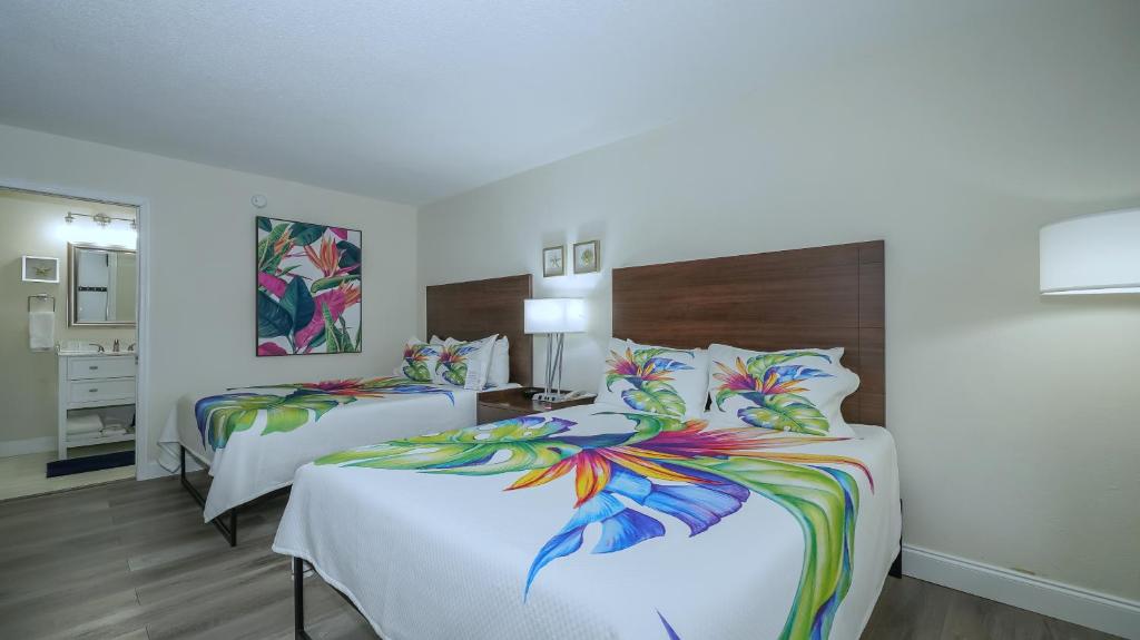 a hotel room with two beds with colorful sheets at All-New, Private, Huge TV, Heated Pool, Tiki Bar in Sarasota