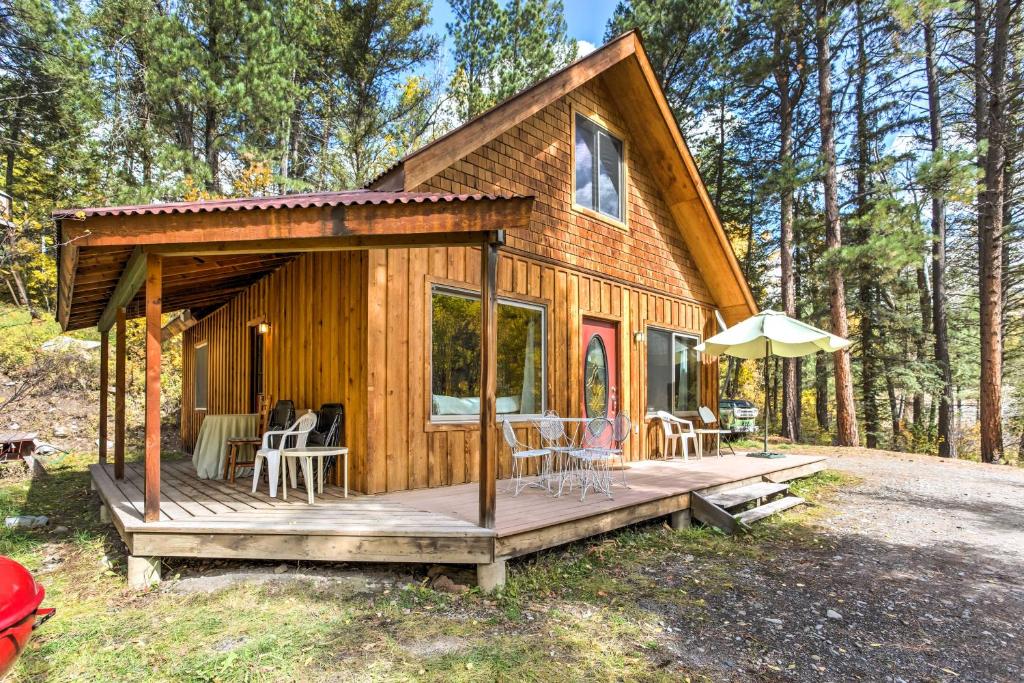 Cette cabine en bois dispose d'une terrasse avec des chaises et un parasol. dans l'établissement Marble Hideaway Cabin with Mountain Views and Deck!, à Marble