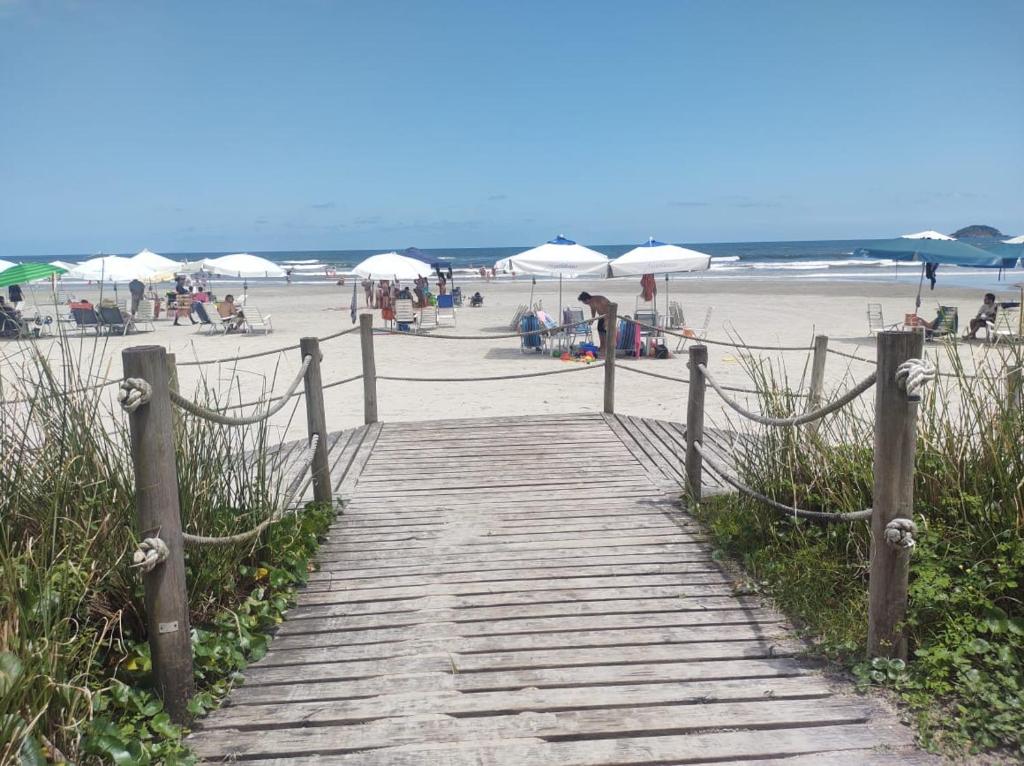 einen Holzweg, der zu einem Strand mit Sonnenschirmen führt in der Unterkunft APARTAMENTO RIVIERA DE SÃO LOURENÇO in Riviera de São Lourenço