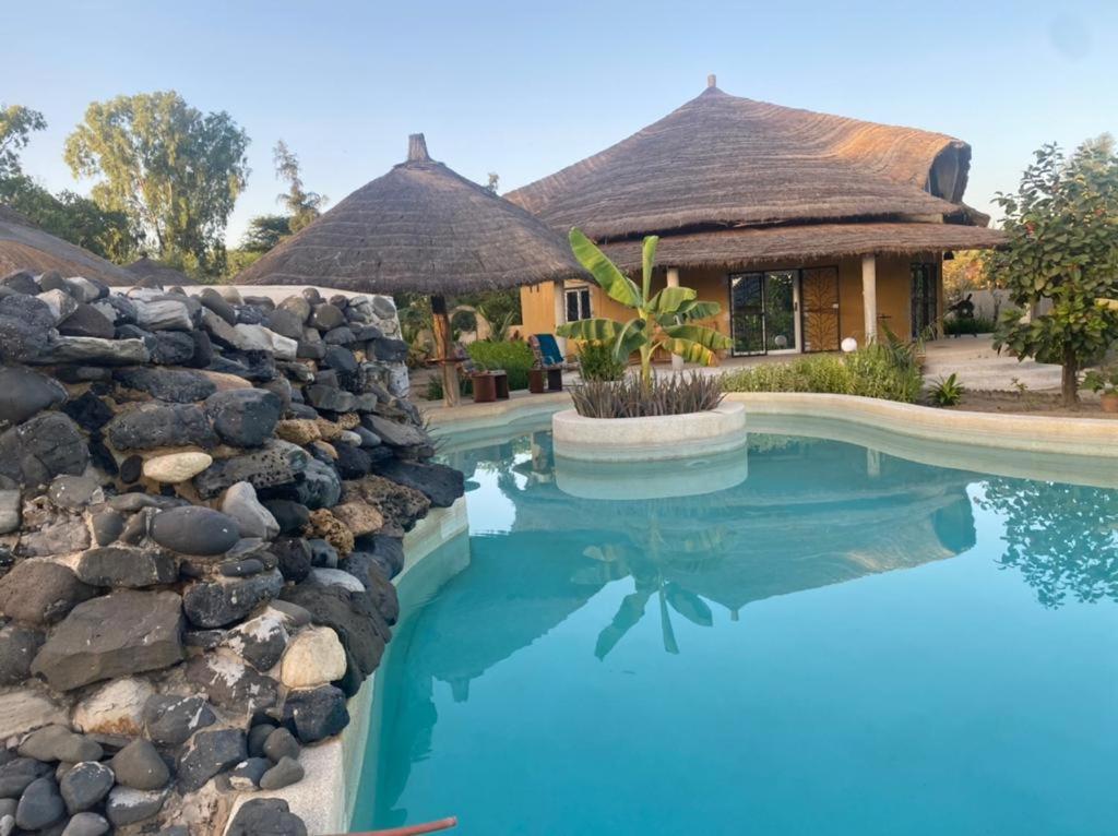 a house with a swimming pool and a stone wall at Villa avec piscine à Ndangane in Ndangane