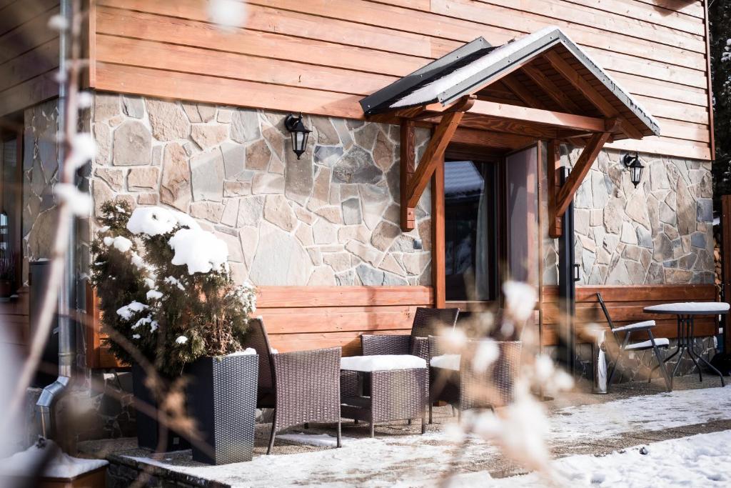 a patio with chairs and tables and a stone building at Chata Eva in Jezersko