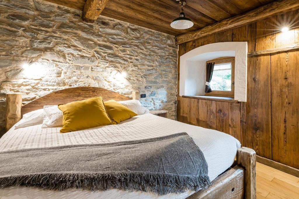 1 dormitorio con 1 cama en una pared de piedra en Chambres d'Hôtes - Li Tzatagni, en Pontboset