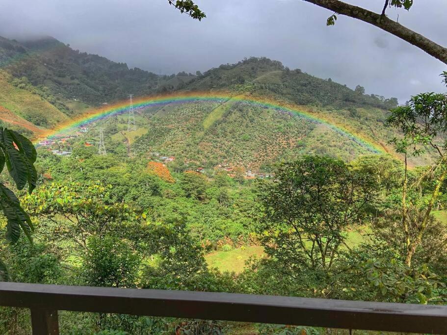 a rainbow over a hill with a town at Modern cabin nestled in mountain nature. Paradise! in Orosí