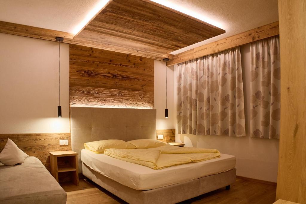 - une chambre avec un grand lit et un plafond en bois dans l'établissement GSCNARA - APARTMENT LIN, à Antermoia