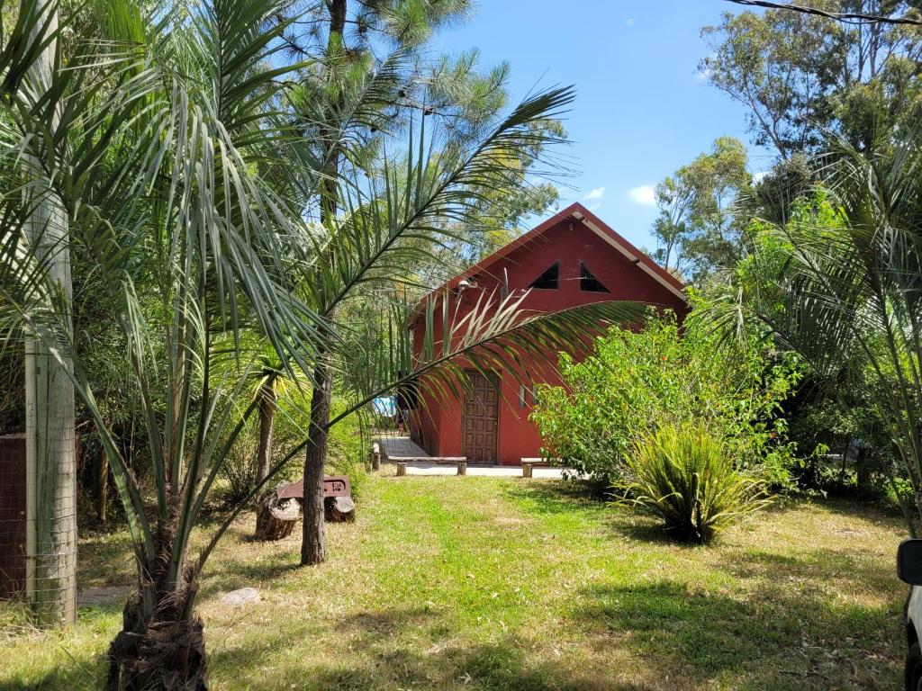 un edificio rojo en medio de un patio con árboles en Lo de RO, en La Pedrera