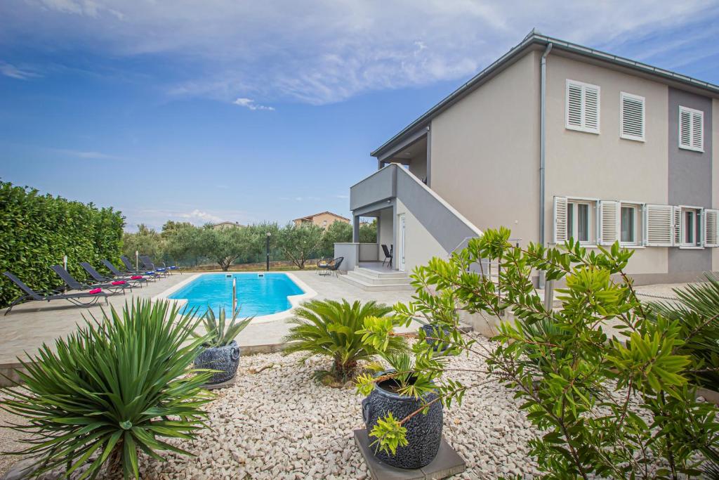 a house with a swimming pool and plants in front of it at Vila Rozarija in Trogir