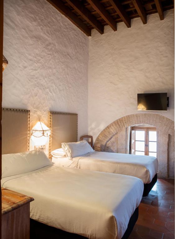 a bedroom with two beds in a room at Hotel Tugasa Convento San Francisco in Vejer de la Frontera