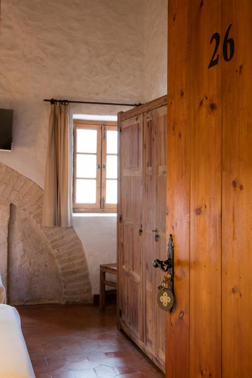 a bedroom with a wooden door with a window at Hotel Tugasa Convento San Francisco in Vejer de la Frontera
