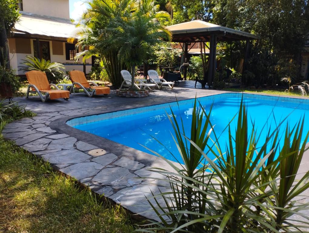 a swimming pool in a yard with chairs and a gazebo at Los Tangueros in Puerto Iguazú