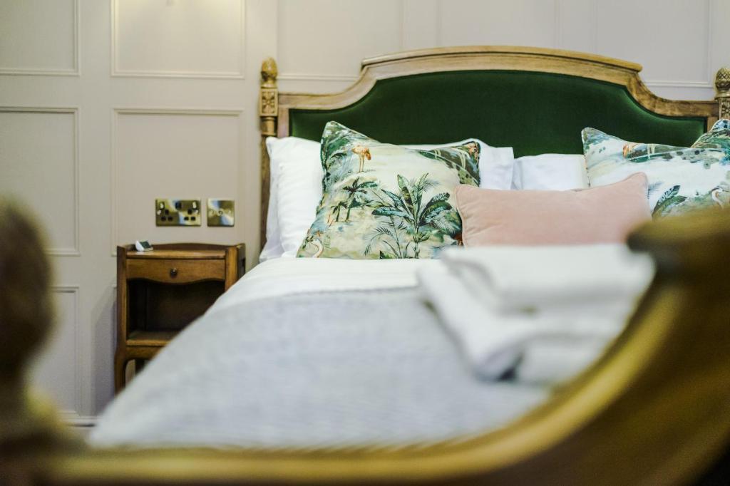 a bed with a green headboard and pillows at Russell Court by Orenda-Luxe in Llandudno