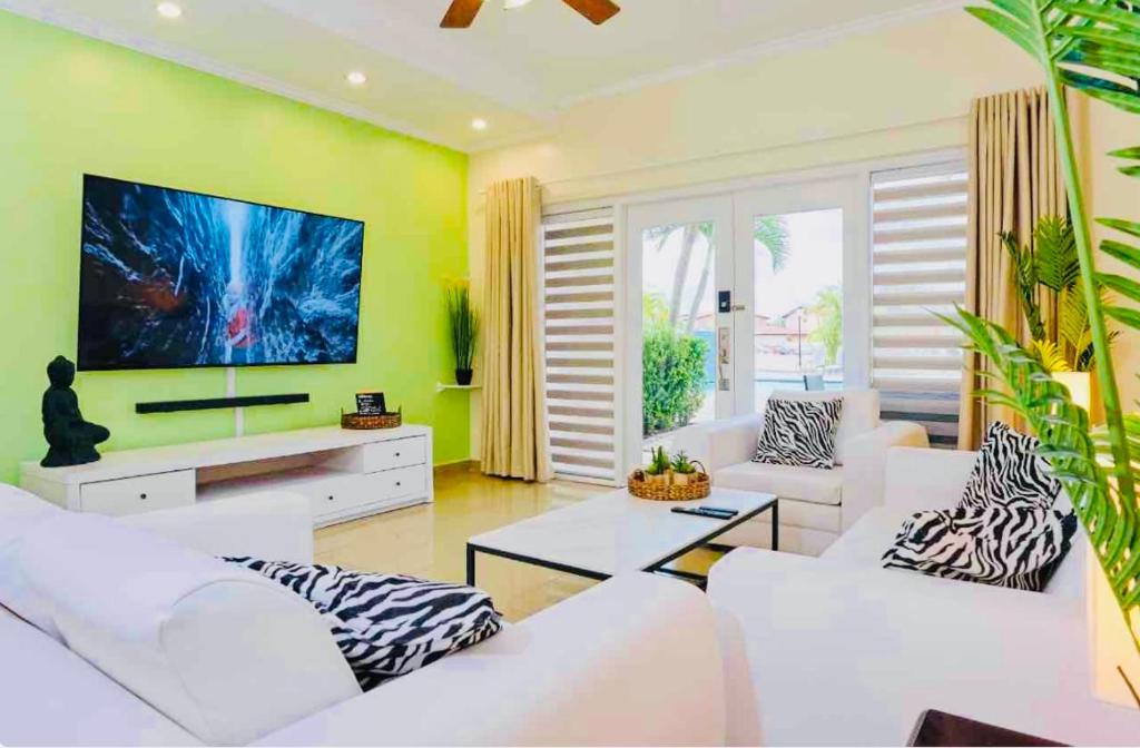 a living room with white furniture and a flat screen tv at Eagle Beach Aruba Breeze Condominium Lime in Palm-Eagle Beach