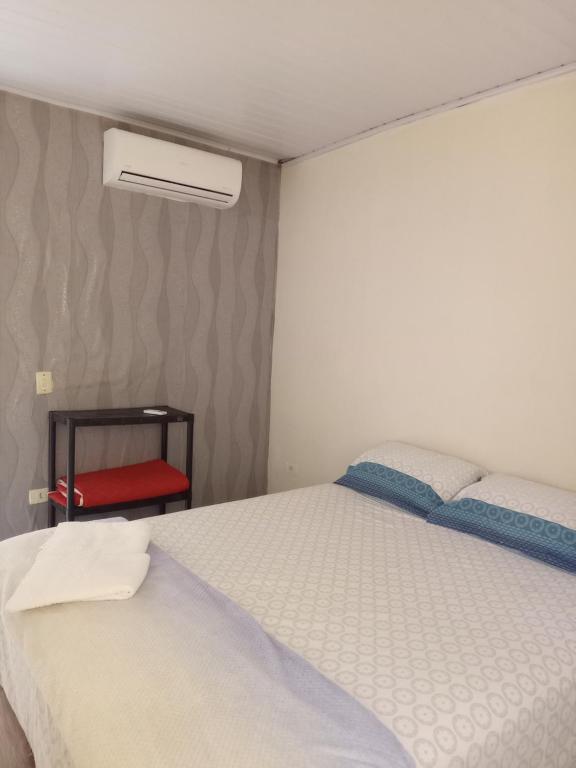 1 dormitorio con 1 cama blanca y 1 silla roja en Casa Lins, en Foz do Iguaçu