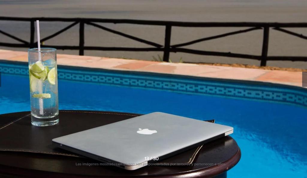 un ordenador portátil sentado en una mesa junto a una piscina en Lofts y cabañas del Puerto en Ituzaingó
