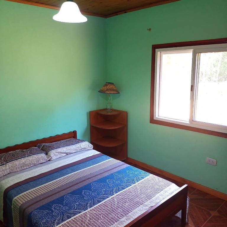 a bedroom with a bed and a window at Cabaña Don Lorenzo in Puerto Victoria