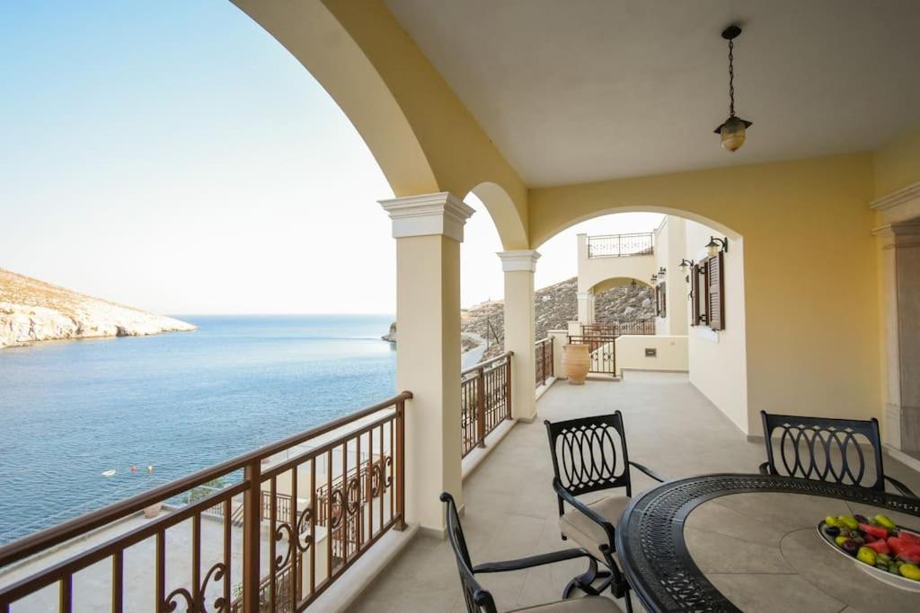 a balcony with a table and chairs and the ocean at Vlihadia Bay Luxury Villa in Kalymnos