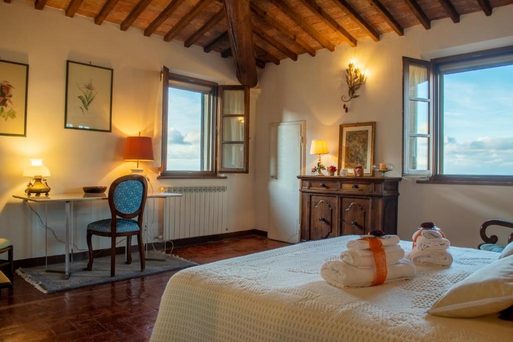 a bedroom with a bed and a desk and windows at La Torre del Conte,Free Wi-fi, Amazing view in Montepulciano