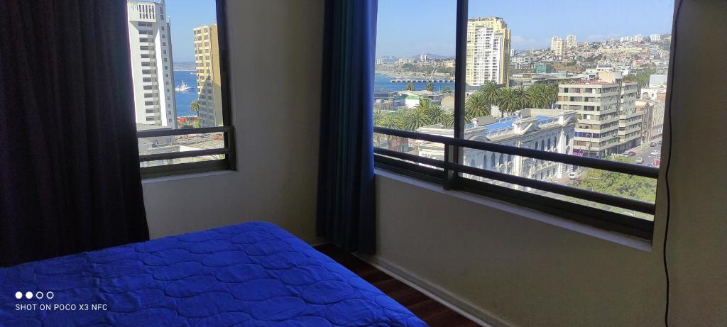 a bedroom with a bed and two large windows at Vista Mar Loft Apartment Downtown Valparaíso in Valparaíso