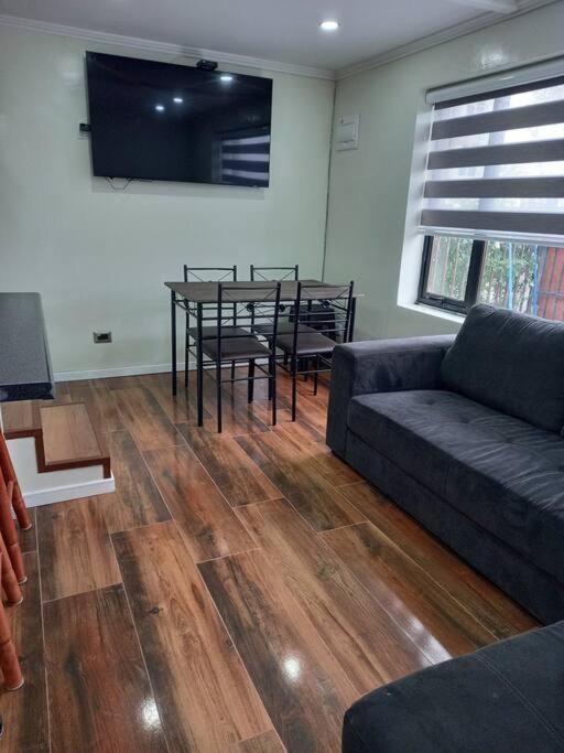 a living room with a couch and a table with chairs at Cabañas y Departamentos Las Palmas, Temuco Depto 1 in Temuco