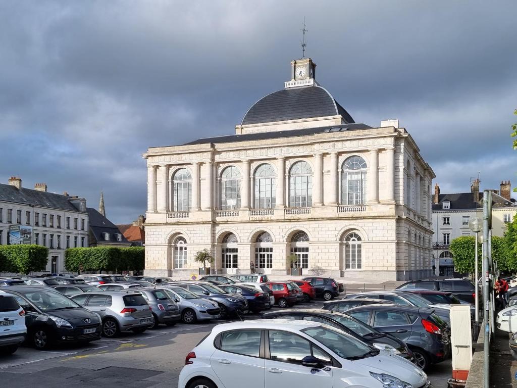 a large building with cars parked in a parking lot at Bel Appart - Rez-de-chaussée - Hyper centre in Saint-Omer
