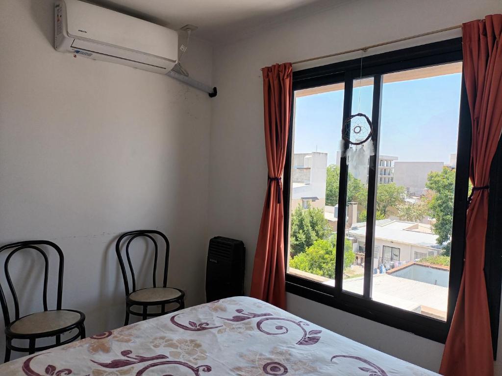 um quarto com uma janela, uma cama e cadeiras em Departamento con Cochera Muy Luminoso Gualeguaychú em Gualeguaychú