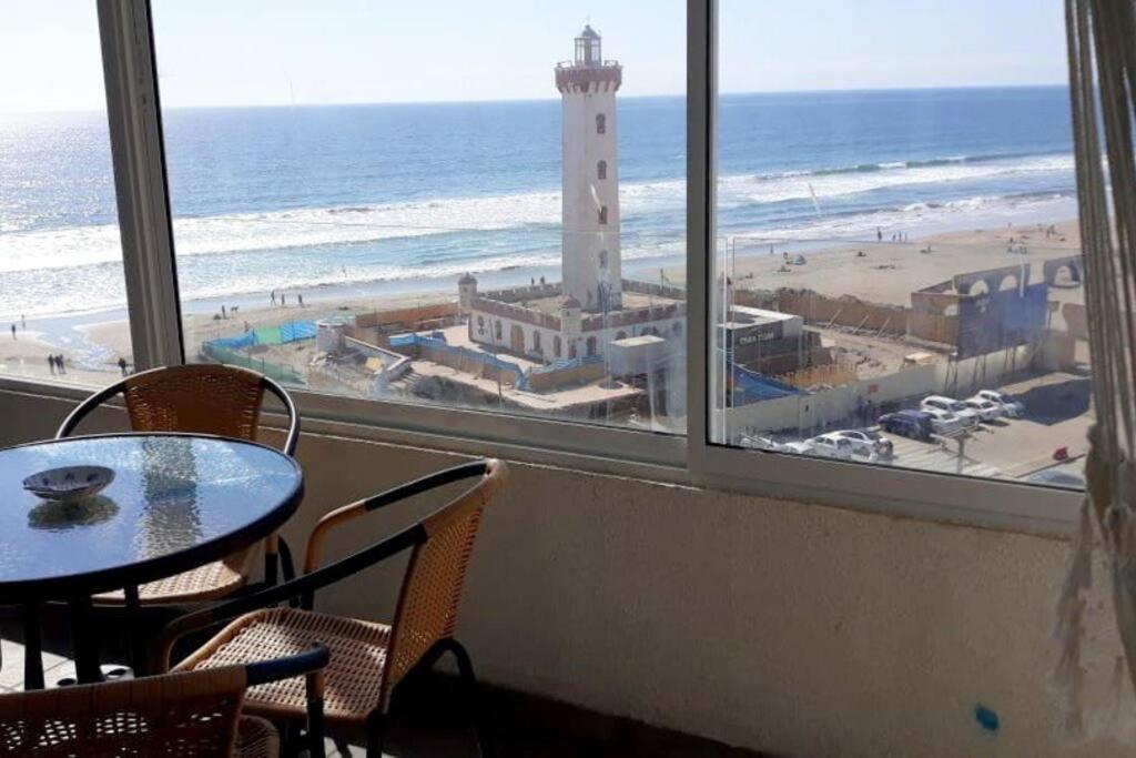 Zimmer mit einem Tisch, Stühlen und einem Leuchtturm in der Unterkunft Depto. frente a la playa con hermosa vista al mar y faro La Serena in La Serena
