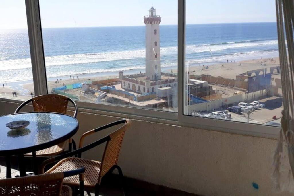 a room with a table and chairs and a lighthouse at Depto. frente a la playa con hermosa vista al mar y faro La Serena in La Serena