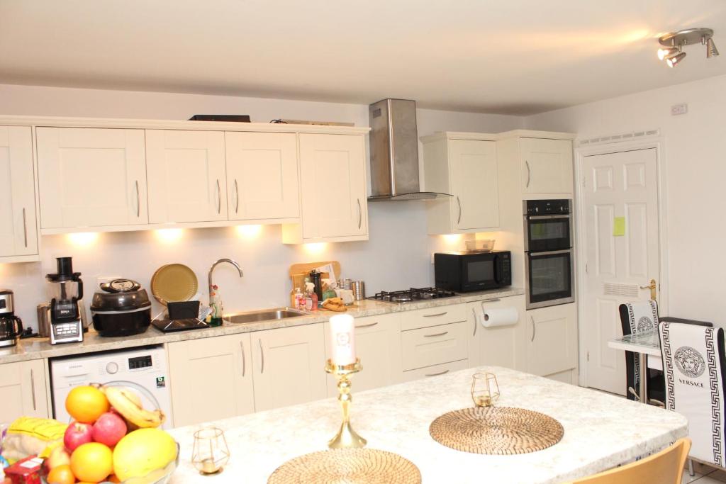 a kitchen with white cabinets and a counter with fruits on it at Elegant Guest House in Spinney Hill