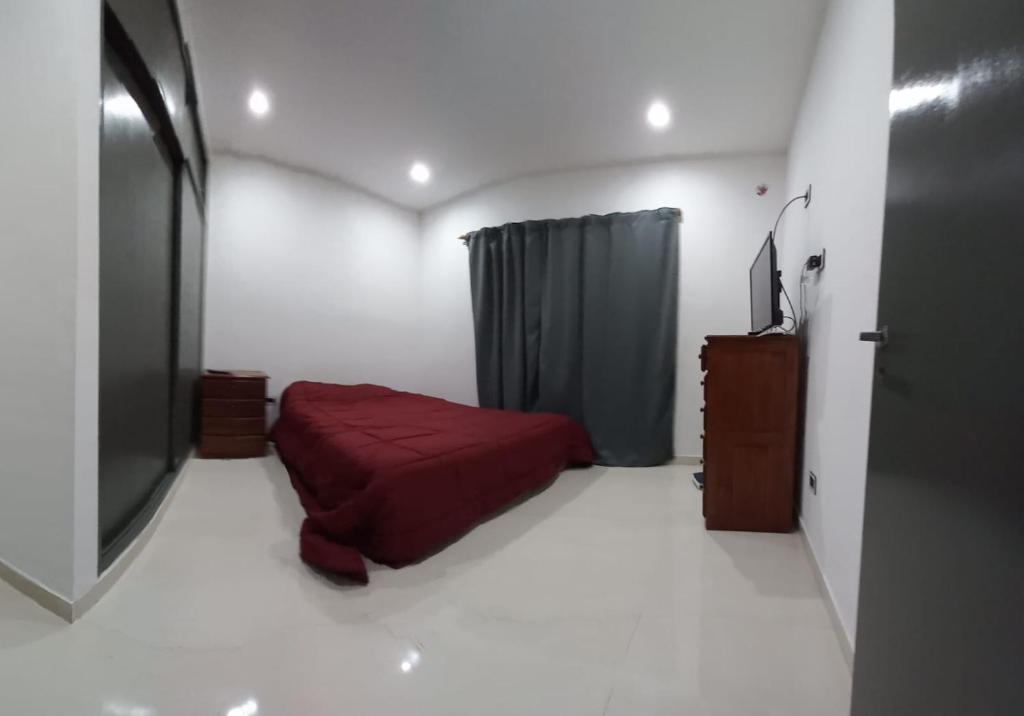 1 dormitorio con cama roja y TV en Dpto estrada en Ezeiza