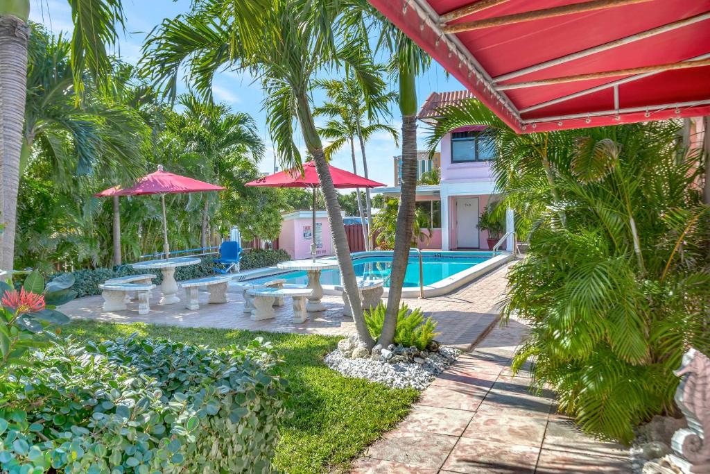 a resort with a swimming pool and palm trees at Seahorse Guesthouse in Pompano Beach