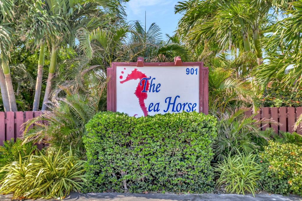 a sign that says like a horse on top of a bush at Seahorse Guesthouse in Pompano Beach