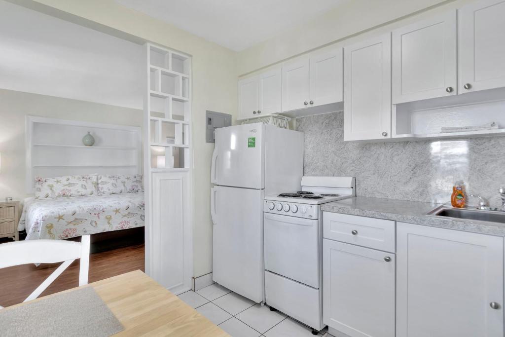 a kitchen with white cabinets and a white refrigerator at Seahorse Guesthouse in Pompano Beach