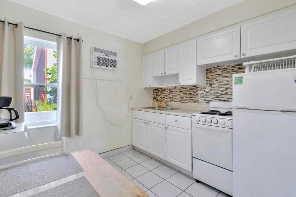 a white kitchen with white appliances and a window at Seahorse Guesthouse in Pompano Beach
