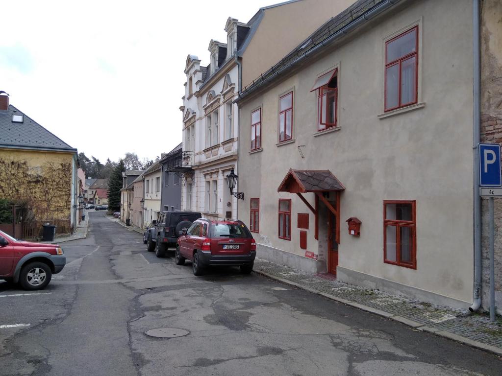 une rue avec des voitures garées sur le côté d'un bâtiment dans l'établissement Atlantis Apartmán 3, à Klášterec nad Ohří