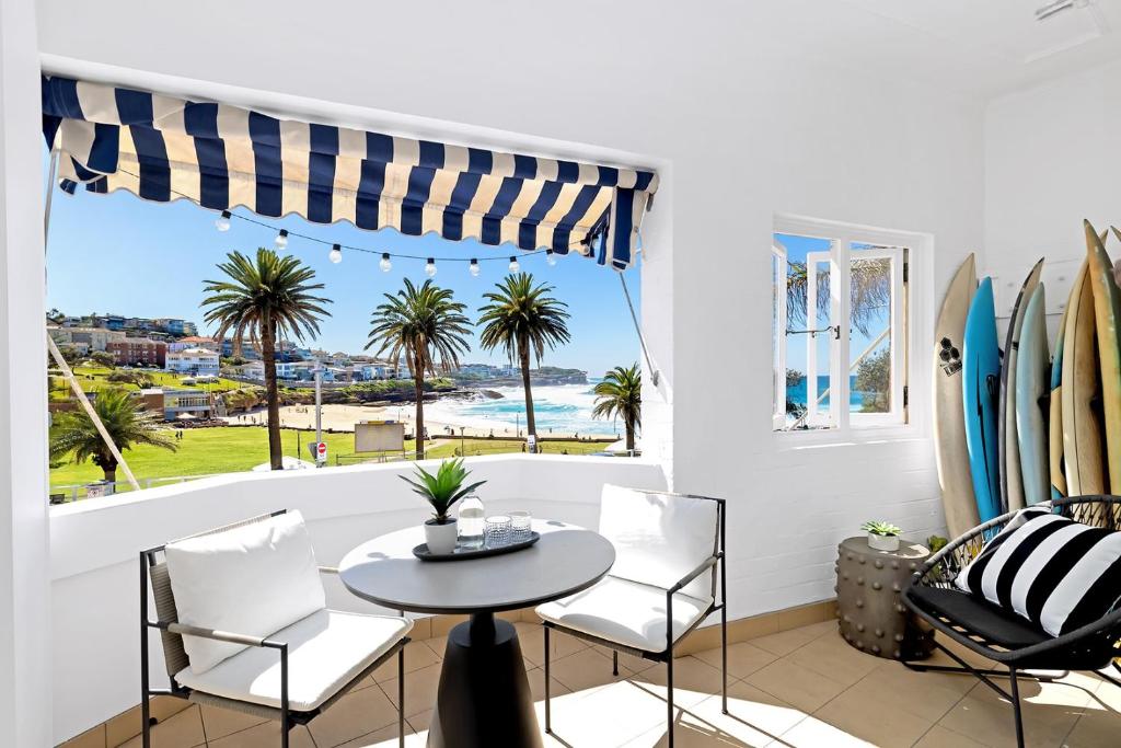 uma sala de jantar com uma mesa e cadeiras e uma janela em Absolute Seafront Bronte em Sydney