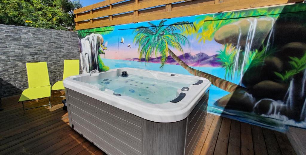 bañera de hidromasaje en una terraza con un mural en "Chez Claudia "charmant logement avec jacuzzi privatif en toute intimité sur belle terrasse extérieure en bois et piscine, en Courcelles Sucrerie