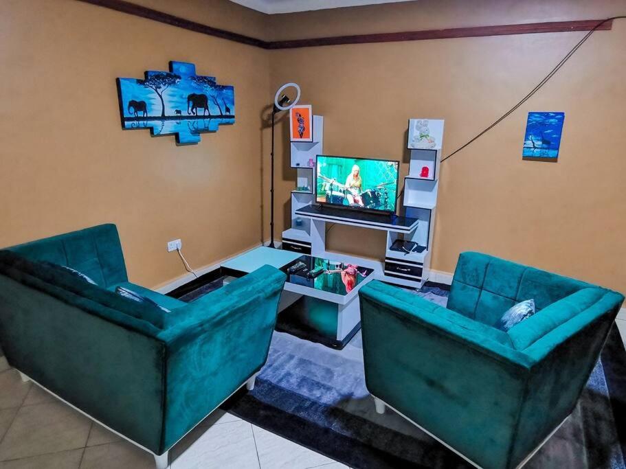 a living room with two green chairs and a television at Lima's Vacation 1BR Apt with Wi-Fi & Netflix in Kampala, Namugongo road in Kampala