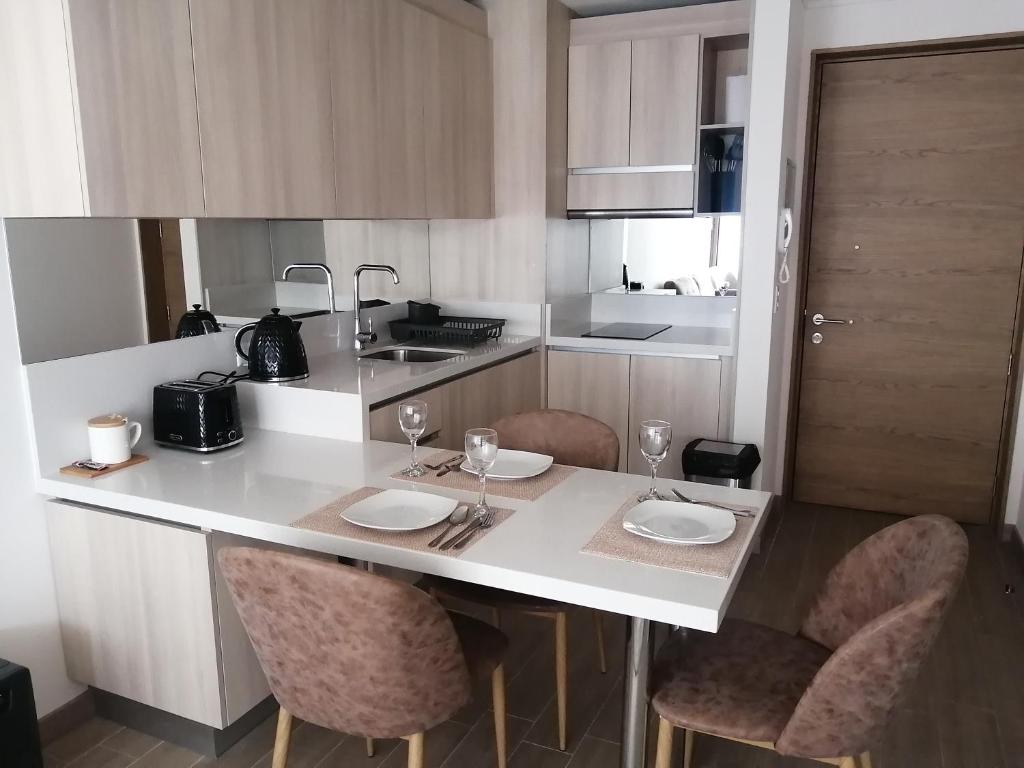 a kitchen with a white counter with chairs and glasses at Claro Centro Temuco in Temuco