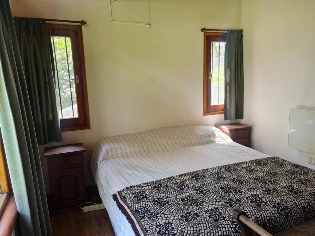 1 dormitorio pequeño con 1 cama y 2 ventanas en Cabaña en los Acantilados en Mar del Plata