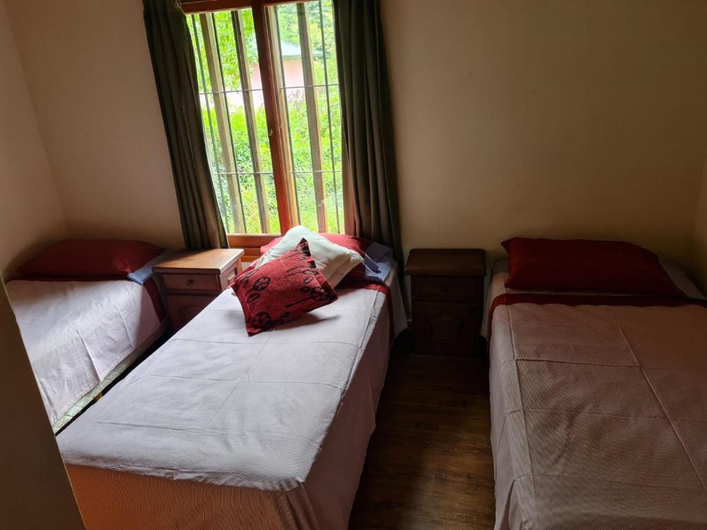two beds in a room with a window at Cabaña en los Acantilados in Mar del Plata